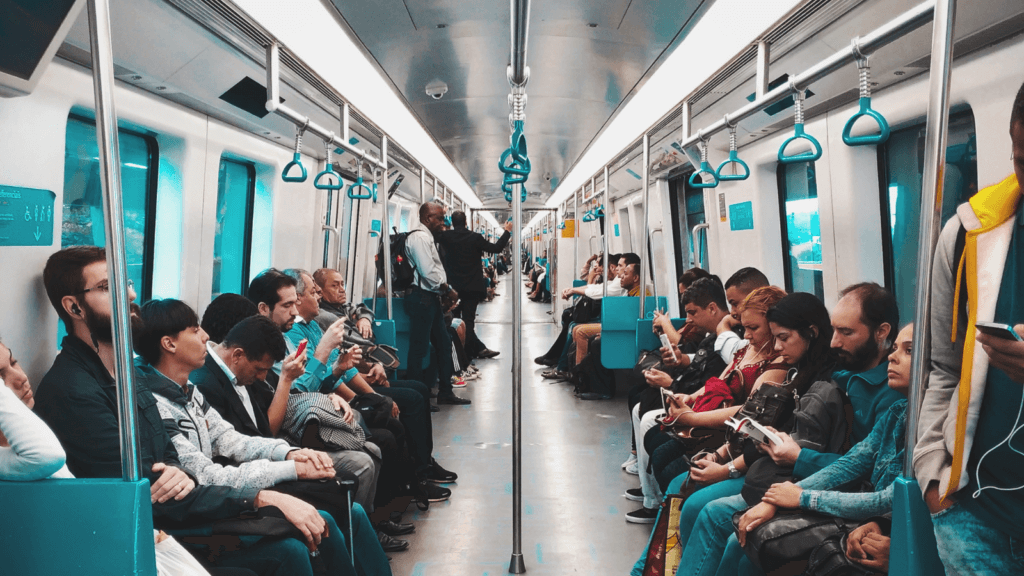 passengers sitting and standing inside a silver and blue subway car