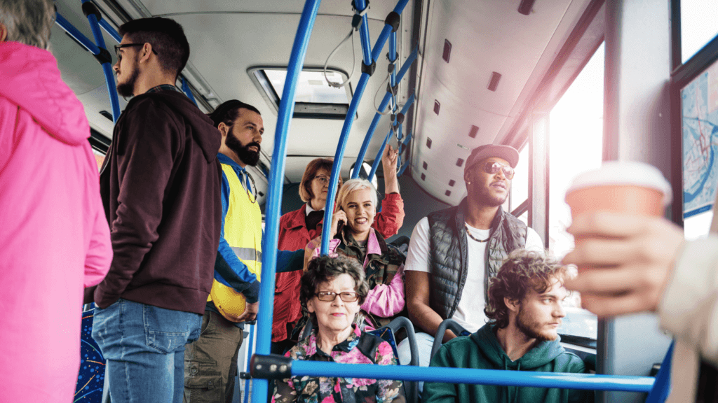 passengers sitting and standing inside a city bus with blue handrails